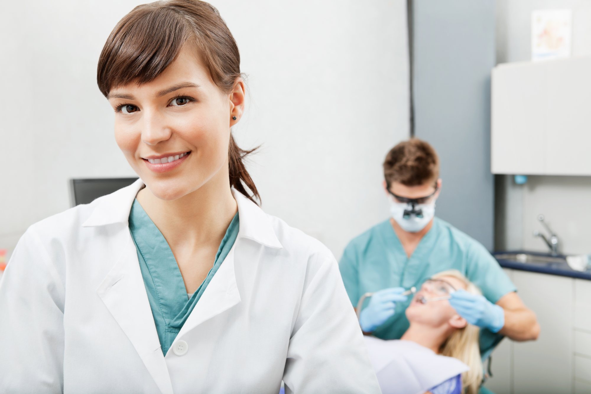 Profissional da clínica sorrindo, com a equipe atendendo ao fundo